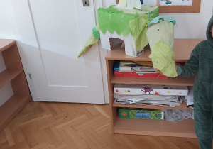 Chłopiec pokazuje dinozaura zrobionego z kartonu