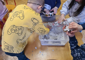 Zabawa badawcza z wykorzystaniem piasku i wykrojników w kształcie dinozaurów